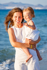 Portrait of mother and little daughter on the sea beach in Greece