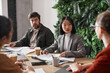 © Seventyfour - Portrait of elegant Asian businesswoman talking to colleagues during business meeting at table in office, copy space