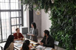 © Seventyfour - High angle portrait of diverse group of business people meeting at table in modern office interior decorated by plants, copy space