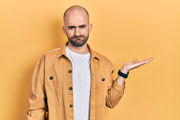 Sticker - Young bald man presenting with open palms, holding something depressed and worry for distress, crying angry and afraid. sad expression.