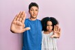 © Krakenimages.com - Young hispanic family of brother and sister wearing casual clothes together doing stop sing with palm of the hand. warning expression with negative and serious gesture on the face.