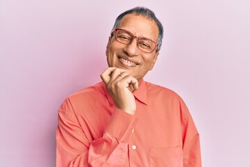 Poster - Middle age indian man wearing casual clothes and glasses looking confident at the camera with smile with crossed arms and hand raised on chin. thinking positive.