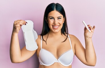 Poster - Beautiful brunette woman holding sanitary pad and cotton tampon smiling with a happy and cool smile on face. showing teeth.