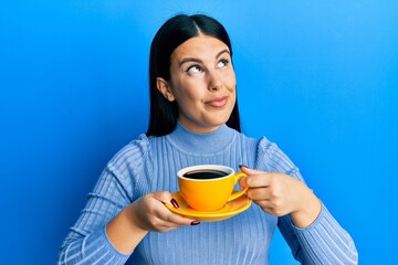 Sticker - Beautiful brunette woman drinking a yellow cup of black coffee smiling looking to the side and staring away thinking.