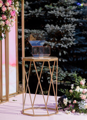 Wall Mural - Front view of glass box standing on the table near the arch before wedding ceremony.