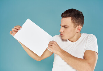 Happy guy shows a flyer in his hand on a blue background advertising mockup