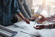 © amnaj - Architects man discuss design ideas using blueprints at the office.