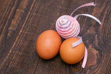 Three Chicken Eggs On A Wooden Surface One Egg Is Decorated With An Easter Ribbon