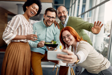 Wall Mural - Multi-ethnic group of business co-workers taking selfie and having fun on lunch break in the office.