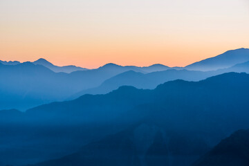 Wall Mural - Layers of magnificent mountains with colorful clouds background at sunrise view