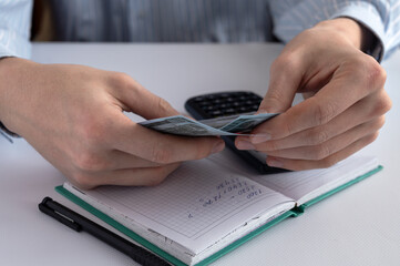 Wall Mural - Men's hands with money, notepad, calculator and pen on a white background. Home finance. Financial accounting. Business concept. Close-up