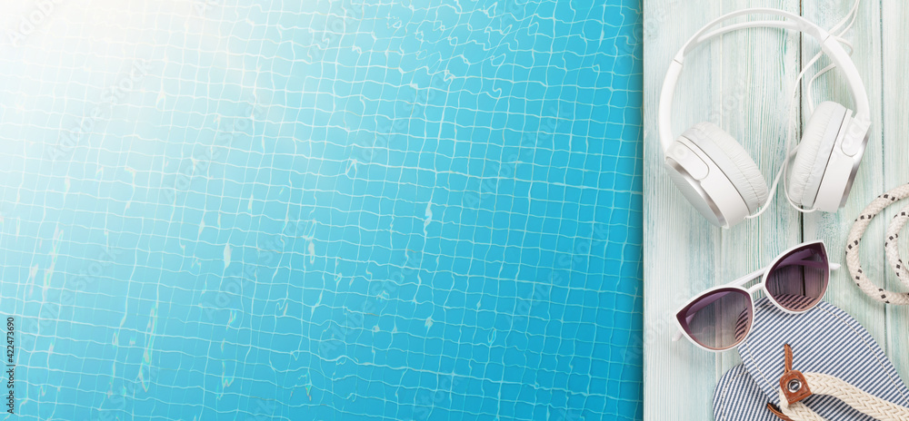 Pool and beach items, headphones and water surface of swimming pool - obrazy, fototapety, plakaty 