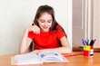 © Ludmila - A teenage girl sits at a table at home and is engaged in school lessons.