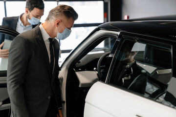 Sticker - Mid white manager in face mask showing car to customer in showroom