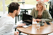 © Drobot Dean - Man and woman using laptop and writing down notes while sitting in cafe