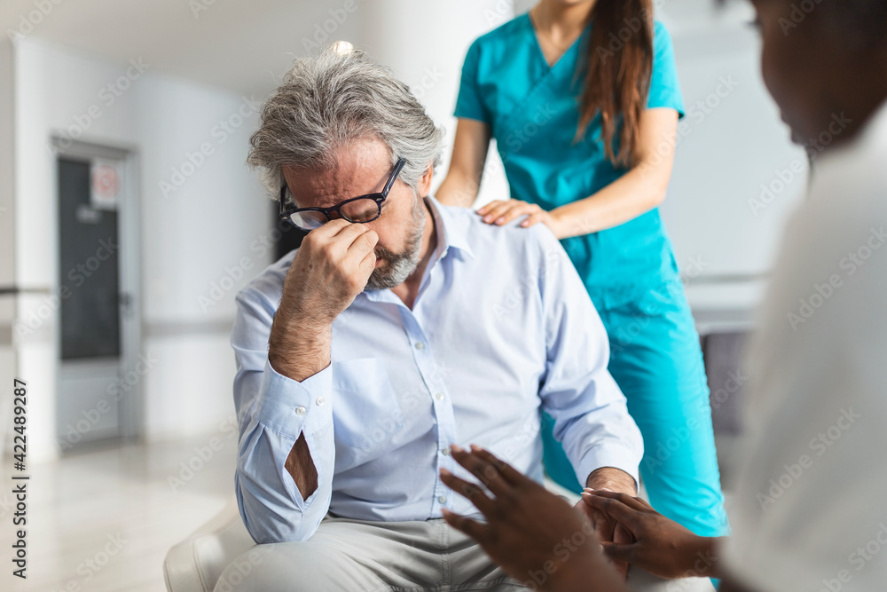 Person Crying Console Doctor consoling upset man in hospital waiting room. Patient receiving ...