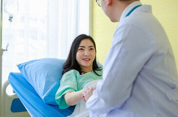 Female patient on sofa in hospital watching clipboard with doctor