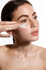 Beauty girl applying moisturizing cream on her face. Photo of young woman with flawless nude skin on white background rub scrub mask to calm down inflammation, better skin-tone