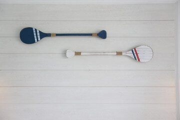 White and blue paddle are on the white wooden walls.