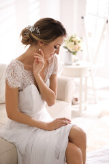 Poster - Gorgeous bride in beautiful wedding dress sitting on sofa in room