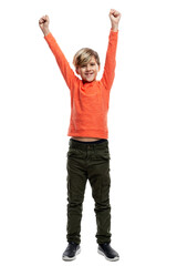 A joyful 9-year-old boy in an orange sweater and green trousers raised his hands up. The happiness of victory and celebration. Full height. Isolated on white background. Vertical.