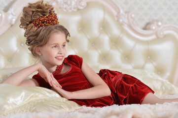 cute little girl in red dress lying on bed
