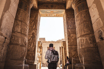 person with backpack exploring medinet habu temple in luxor egypt