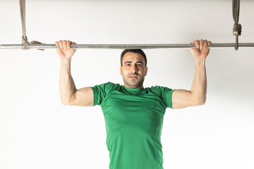 Athlete man doing pull-ups on white background.