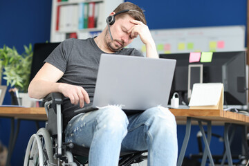 Disabled man sleeping in wheelchair with laptop on his lap