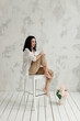 © Natalia - brunette girl sitting on a high white chair with a bouquet of flowers on the floor