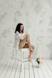 © Natalia - model shooting in the studio girl sitting on a white chair with a bouquet of flowers