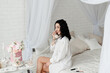 © Natalia - brunette girl with bare legs in a white shirt talking on the phone while sitting on the bed