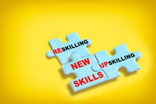 New Skills Development Concept And Changing Skill Demand Idea . Reskilling, Upskilling And New Skills Written On Blue Puzzle Isolated On Yellow Background