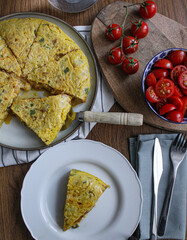 Poster - Spanish Omelette dinner from top view. Sliced tortilla on table with a served slice. Side salad made of tomatoes. 