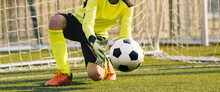 Young Football Galkeeper Catching Soccer Ball. Soccer Goalie In Action Saving Ball In A Goal
