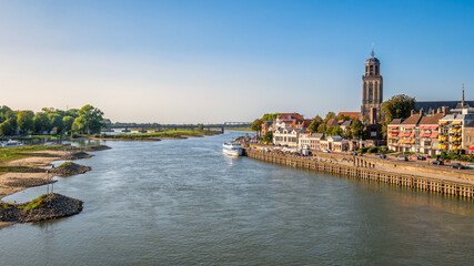 Dutch landschape near the Hanze city of Deventer. The famous Wilhelmina Bridge and the St. Nicholas Church or the Berg Church can be seen. It is a warm and clear summer September day. 