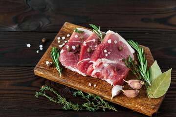 Fresh raw meat sliced with seasonings and spices on a wooden board. 