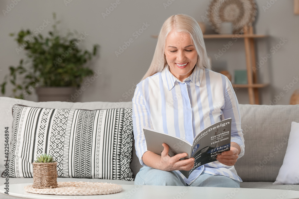 Happy mature woman reading magazine at home