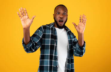 Wall Mural - Shocked African American Guy Raising Hands Posing Over Yellow Background