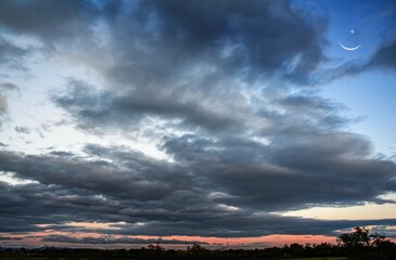 Wall Mural - beautiful dark fluffy cloudy sky with sun rays . crescent moon with beautiful sunset background