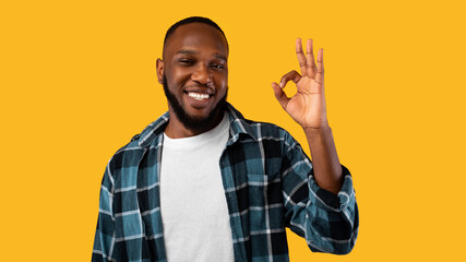 Cheerful African Guy Gesturing OK Sign To Camera, Yellow Background