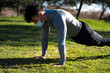 © PEDROMERINO - Young man with mask doing push-ups in a park. training and health with covid