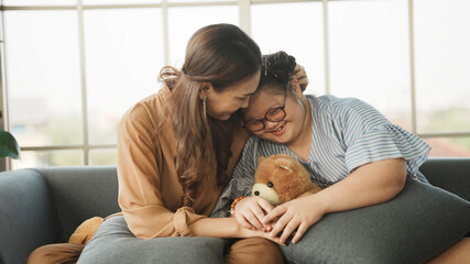 mother supporting sweet down syndrome daughter to learn and relax from the internet, embracing child