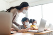 Asian Young Teacher with little boy in protective face masks using laptop for  studying in classroom.