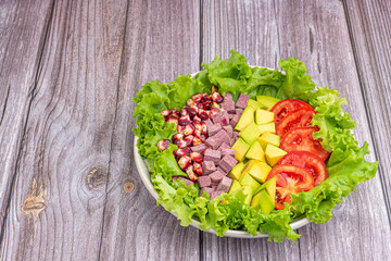 Wall Mural - Green lettuce salad with fresh mixed purple corn, purple yams, avocado, and tomatoes on wooden table background. Space for text. Concept of healthy foods and vegetables