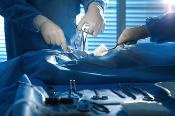 Wall Mural - Professional surgeons with instruments performing operation in clinic, closeup