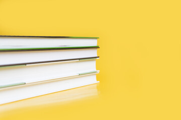 Wall Mural - A stack of books on a yellow background. The books are on a plain background with space for writing. Composition of a reading person.