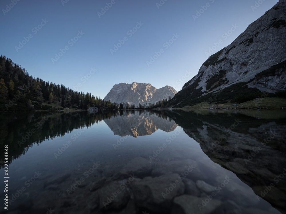 Sunrise mirror reflection of Zugspitze mountain massif in clear calm ...