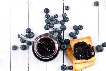 Canvas Print - Top view of blueberries on the table with white bread and jam for breakfast