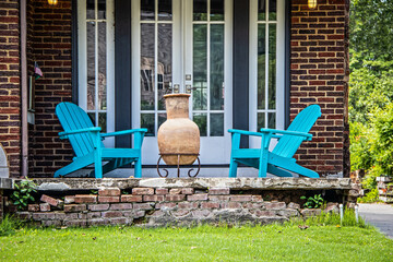 Wall Mural - Two turquoise adirondack chairs and a chiminea on a crumbling brick porch in font of french doors on summer day with tiny American flag displayed